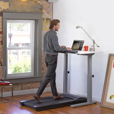 Man walks on the lifespan TR800 treadmill whilst working on his laptop