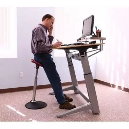 Man leaning into the Mobis 2 seat whilst working at a standing desk 