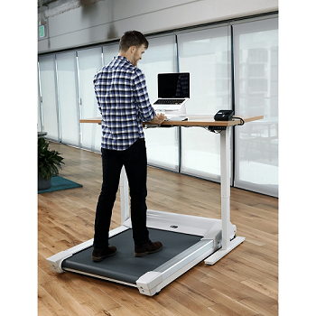 Man walking on treadmill whilst working on his computer