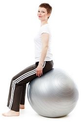 Woman in fitness gear sits upright on a silver exercise ball