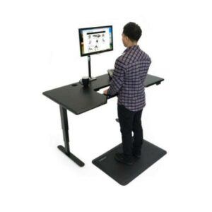 Back view of man standing on anti-fatigue mat whilst working at his standing desk with adjustable keyboard tray