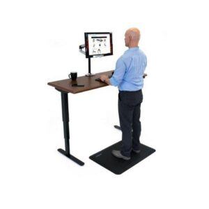 Man typing on keyboard at height adjustable desk whilst standing on an anti fatigue mat