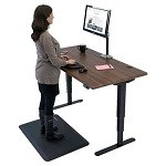 Woman standing on anti-fatigue mat whilst working at a standing desk
