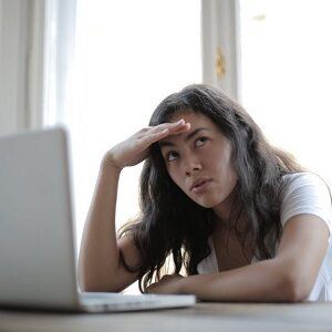 Girl sat in front of laptop with a pensive expression