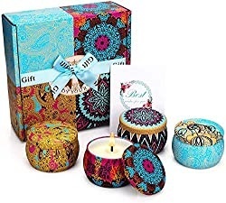 Four vibrantly colored candles with lids in front of presentation gift box