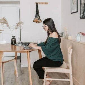 Woman working on laptop at kitchen table