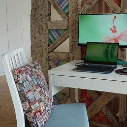 Laptop and monitor on desk with chair and cushion in foreground