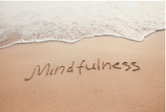 Beach scene with the word mindfulness written in the sand