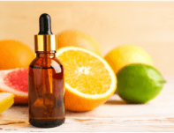 Bottle of essential oil with citrus fruits behind