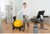 Woman stretching legs as she holds on to an exercise ball chair