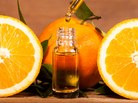 Bottle of orange essential oil between 2 orange halves