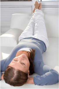 Woman laying on sofa with hands behind her head, relaxing