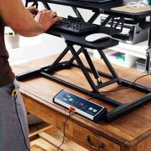 Standing desk converter in raised position with the DT3 console on the main desktop