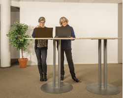 2 women with laptops work at a standing desk