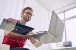 Man using laptop on glass topped desk