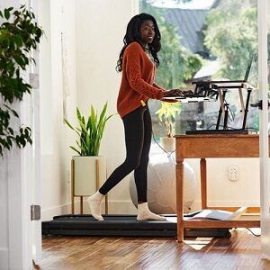 Woman walking on treadmill whilst working from a standing desk converter